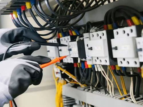Licensed electrician testing a panel with a multimeter